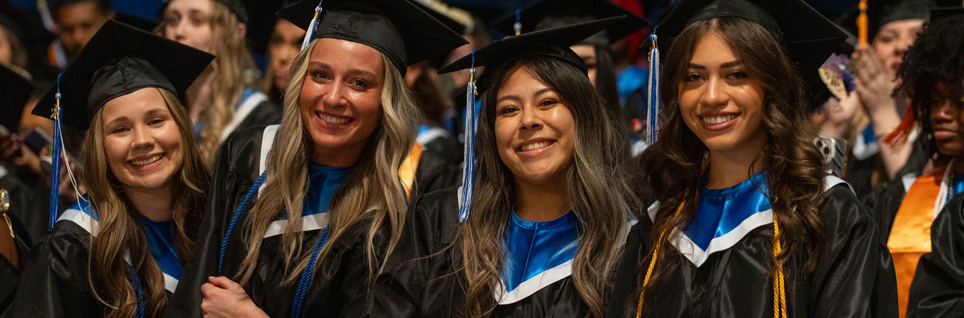 Female Macomb students smiling at the camera during their graduation.