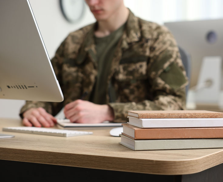 A military student studying on a computer.