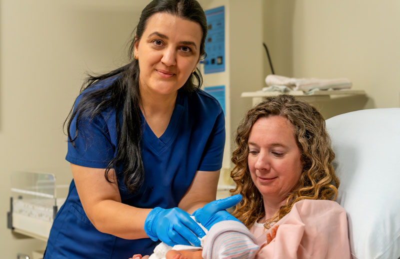 Orgeta Aliaj looking at the camera while helping a new mother.