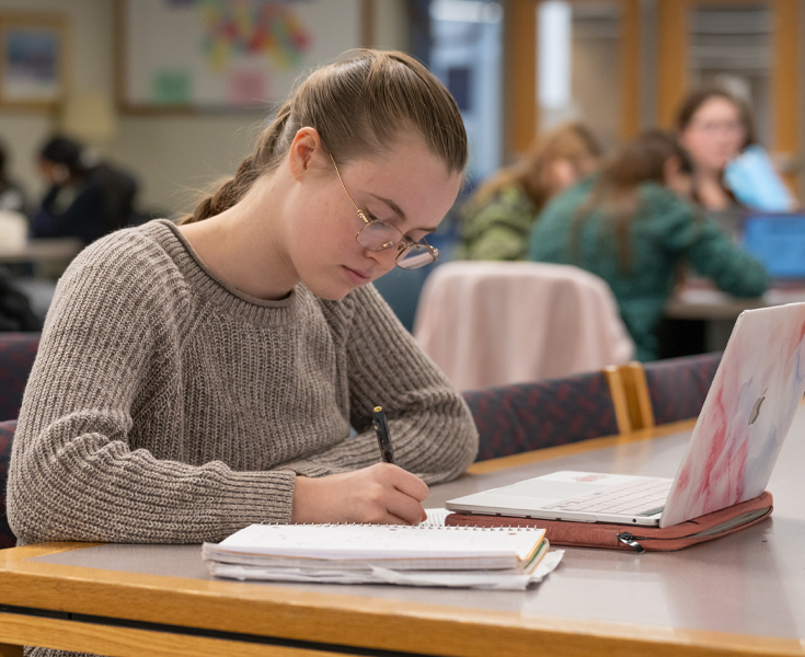 female student looking at camera doing homework.