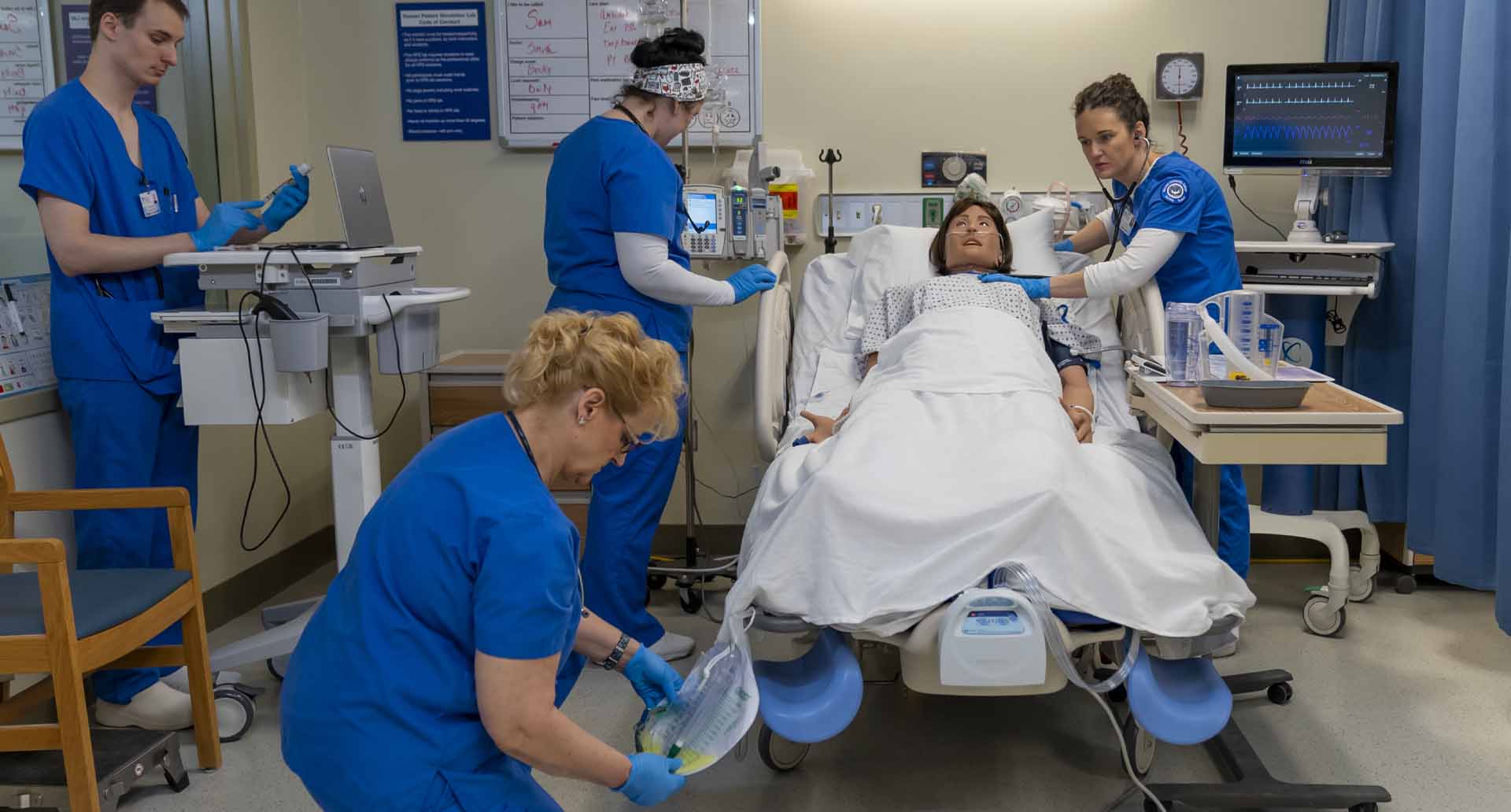 Nursing students (left to right) Dennis Swiontek, 27, of Warren, Kimberly Turner, 60, of Walled Lake, Elyse Vinson, 34, of Clinton Township and Amber Worth, 37, of Mt. Clemens assess the patient and prepare medication in this simulation exercise.  